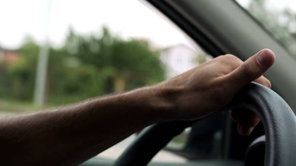 istock Man spinning steering wheel with one hand, car driving lessons, instructor 982007822