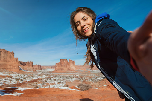 Female traveler taking self portraits with rock formation in the Arches National Park, Utah, USA
