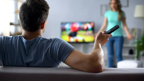 esposa enojada peleas con esposo viendo partido de fútbol, conflicto en las relaciones - television boredom men sofa fotografías e imágenes de stock