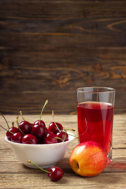 Cherry, apple and a glass of juice on a wooden table