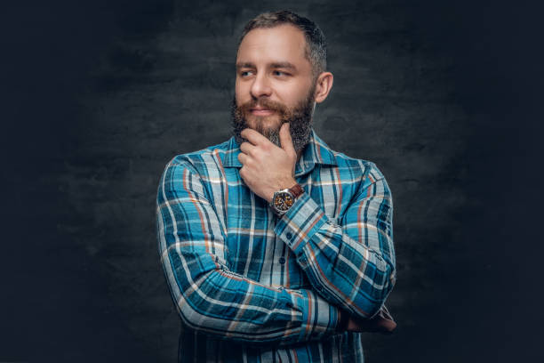 Middle age male in plaid shirt. Portrait of serious middle age bearded male dressed in plaid flannel shirt over grey background. man beard plaid shirt stock pictures, royalty-free photos & images