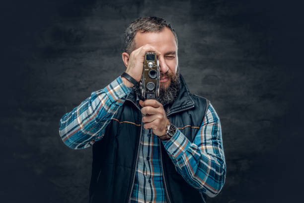 istock Bearded middle age male holds vintage 8 mm video camera. 982024610