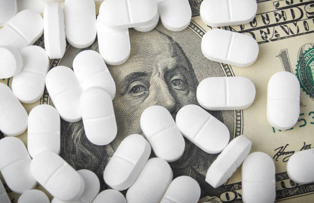 close up of one hundred dollar bill with pills stock photo