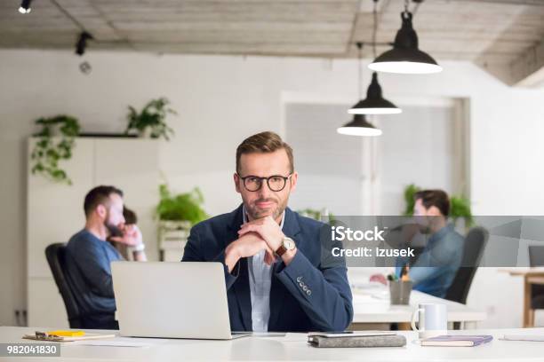 Mature Businessman Sitting At His Desk Stock Photo - Download Image Now - Office, Desk, Front View