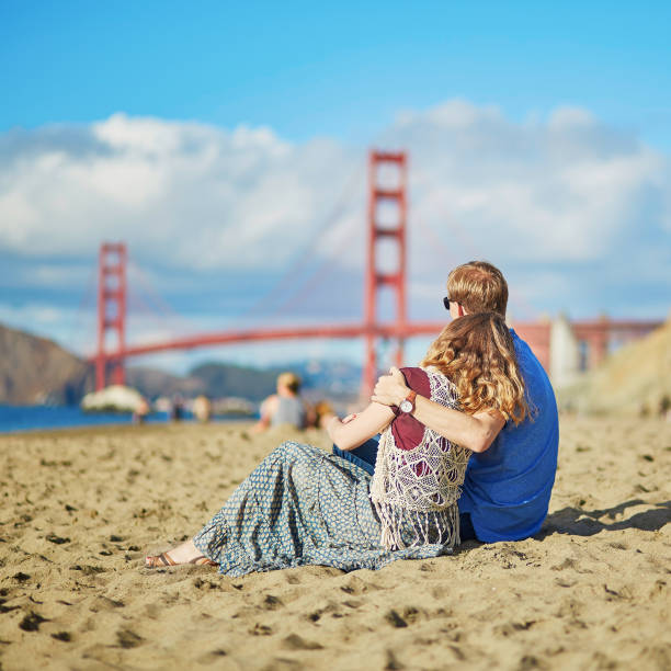 Couple having a date on Baker beach in San Francisco Romantic loving couple having a date on Baker beach in San Francisco, California, USA. Golden gate bridge in the background baker beach stock pictures, royalty-free photos & images
