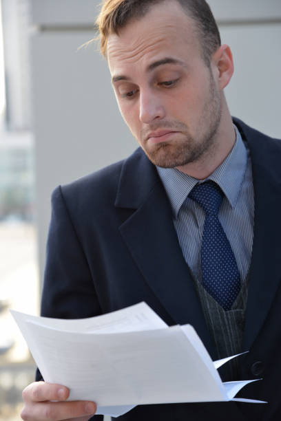 istock tired businessman reading  paper documents 982046386