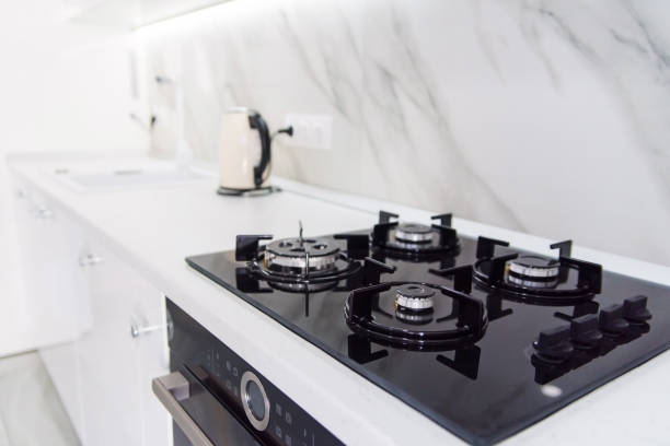 Modern high-tech black gas stove with sensor panel in the bright interior of the kitchen Modern high-tech black gas stove with sensor panel in the bright interior of the kitchen with white marble tiles. burner stove top photos stock pictures, royalty-free photos & images
