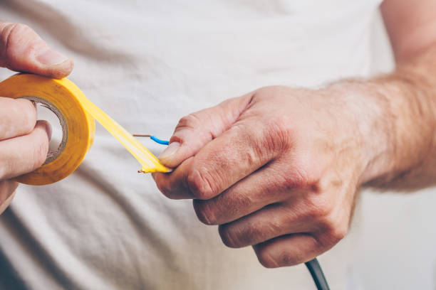 istock Electrician performs electrical work - isolates electric copper cable with insulation tape 982047054