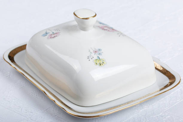 White porcelain butter dish with painted flowers on a white tablecloth