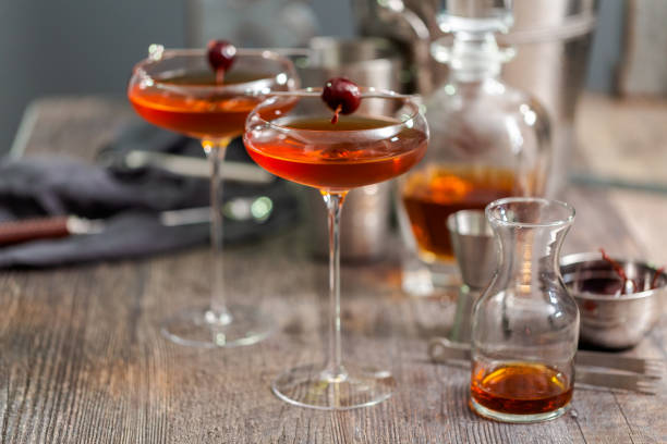 манхэттенский коктейль, украшенный фирменной вишней. - manhattan cocktail cocktail drink cherry стоковые фото и изображения