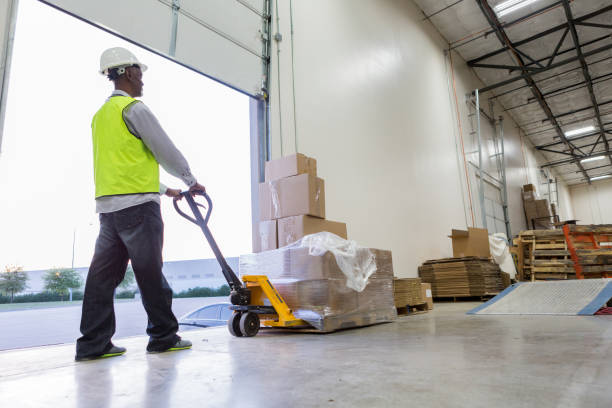 istock Male warehouse worker uses dolly to haul packages 982090458
