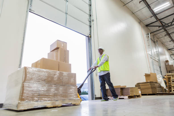 istock Confident male distribution warehouse employee uses dolly 982090460