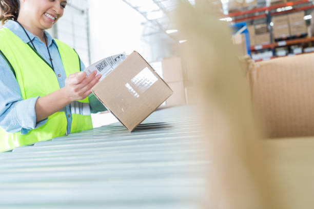 istock Distribution warehouse employee attaches label to package 982090466