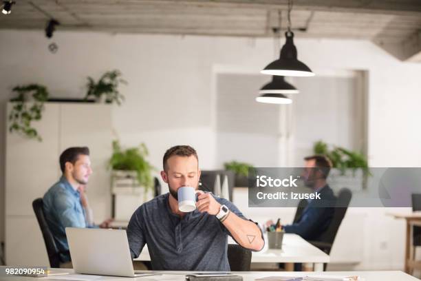 Man Drinking Coffee At His Office Desk Stock Photo - Download Image Now - Computer, Desk, Adult