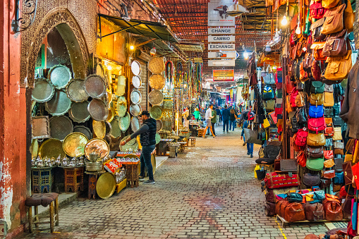 People are walking in one of narrow streets in the souk of Marrakech, Morocco.