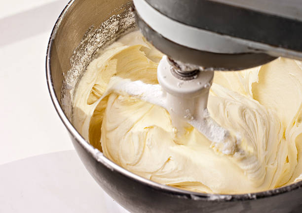 Mixer beating yellow cake icing Electric mixer mixing yellow lemon cream cheese cake frosting.  Shot during actual action and features some blur around beater. icing stock pictures, royalty-free photos & images