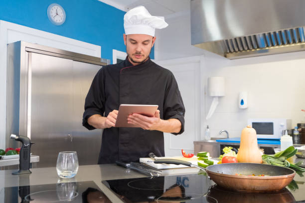 istock young head chef consulting his recipes on the tablet through the internet 982104666