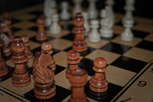 istock Wooden material chess board and chess pieces in low light 982105078