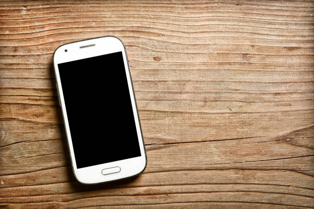 istock the smartphone with the black screen on the wooden table 982108420