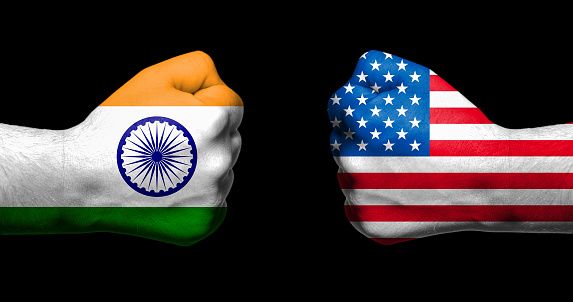 Flags of India and United States painted on two clenched fists facing each other on black background/India - USA tariff conflict concept