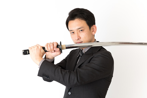portrait of asian businessman using samurai sword isolated on white background