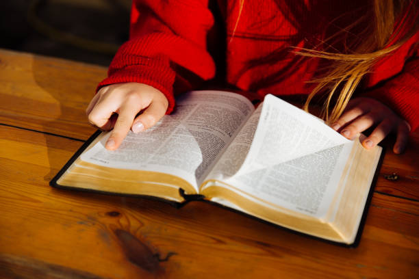 Little girl is sitting and reading a holy book. Concept for faith, hope and spirituality.