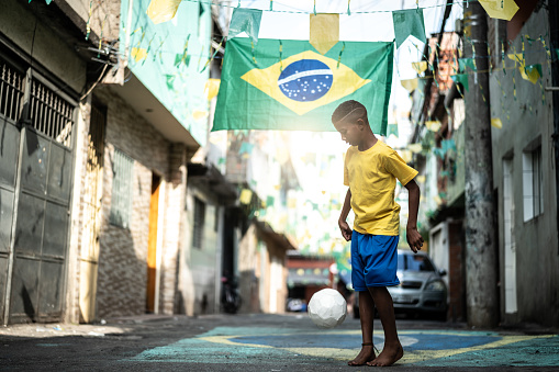 Niño brasileño jugando al fútbol en la calle photo