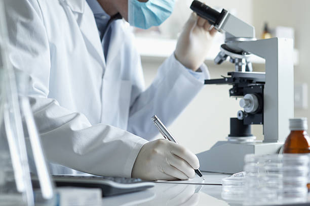 Scientist conducting research with microscope stock photo