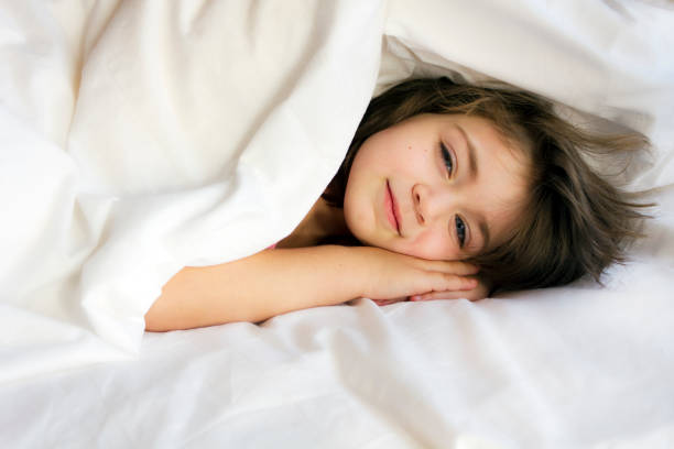 istock Smiling little girl in the bed 982154972