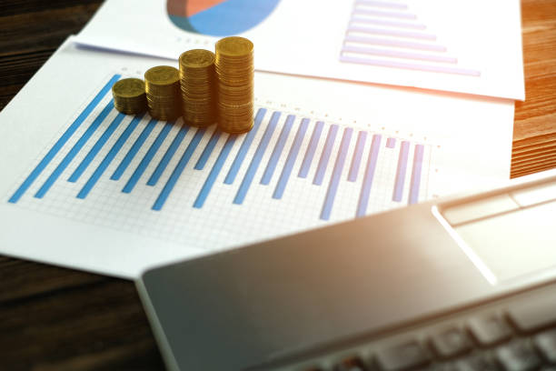 istock Step of coins stacks with notebook laptop computer and financial graph on white paper on working table, business planning vision and finance analysis concept. 982155222