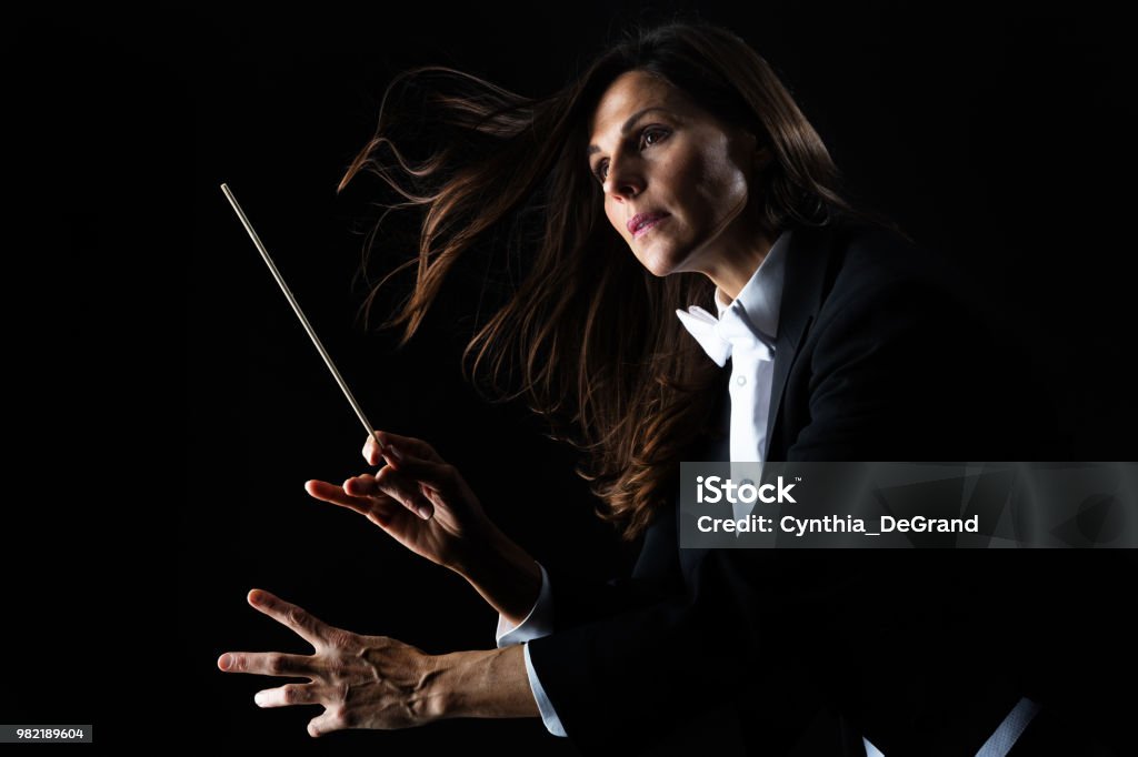 Woman in tuxedo conducting with baton Musical Conductor Stock Photo
