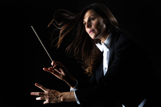 Woman in tuxedo conducting with baton Woman in tuxedo conducting with baton conductors baton photos stock pictures, royalty-free photos & images