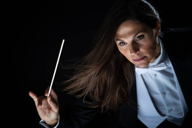 Woman in tuxedo conducting with baton