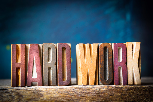 The words HARD WORK spelled with 100+ year old wooden letterpress letter blocks