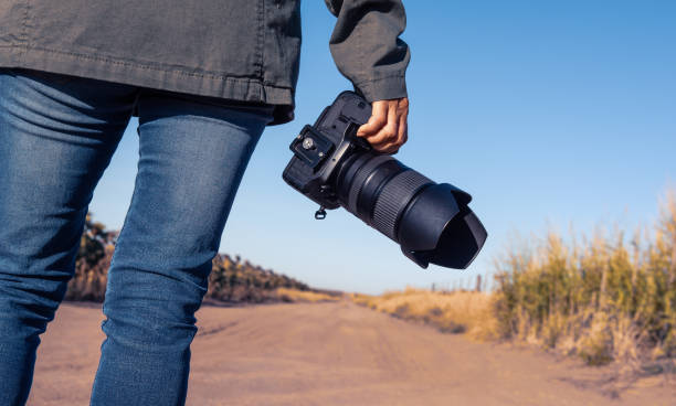 istock Woman holding an DSLR camera from behind and road 982206080