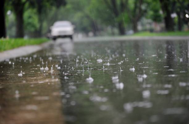 View of the street surface during rain. Water flowing along the street curb during heavy rain. Close up of splashing raindrops and air bubbles. raining outside stock pictures, royalty-free photos & images