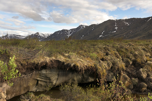 In the subarctic tundra of the Blackstone Uplands, melting permafrost ice is exposed along the gravel Dempster Highway and Ogilvie Mountains in the Tombstone Territorial Park of Yukon Territory.