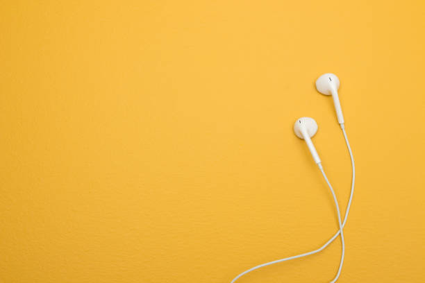 White earphones on yellow background with copy space stock photo