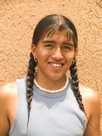 Portrait of a handsome 15 year old Native American boy by an adobe wall