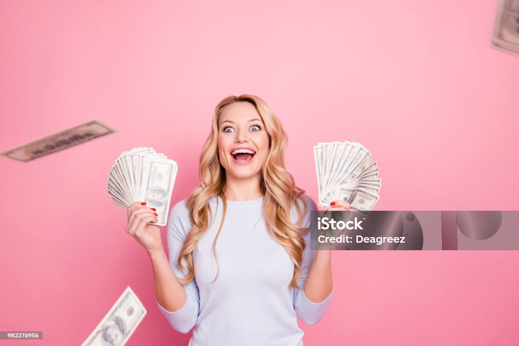 Wow, omg! Portrait of impressed glad  girl having a lot of flying money around her, having unbelievable unexpected reaction, isolated on pink background Currency Stock Photo