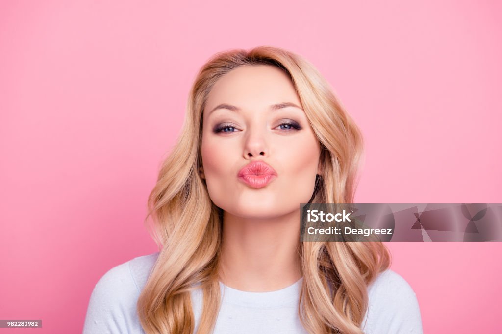 Portrait of cute lovely girl in casual outfit with modern hairdo sending blowing kiss with pout lips looking at camera  isolated on pink background. Affection feelings concept Women Stock Photo