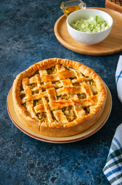 istock Homemade young cabbage pie from flaky dough  served on a plate. Blue stone background. 982336288