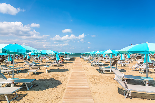Beach chairs and umbrellas in Rimini, Italy during summer day with blue sky. Summer vacation and relax concept