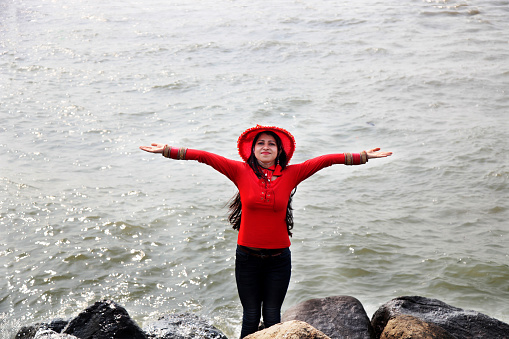Young woman of Indian ethnicity standing near the seashore of Arabian Sea and enjoying fresh air.