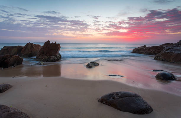 alba colorata sull'oceano con rocce in primo piano - port stephens new south wales australia coastline foto e immagini stock