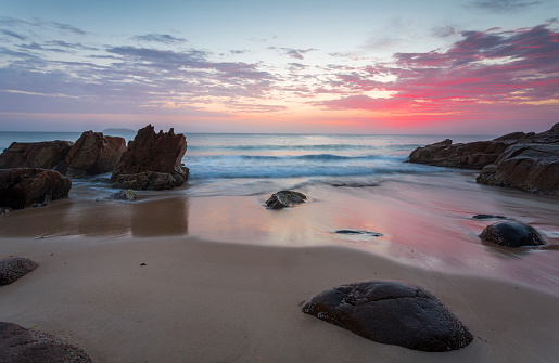 Beautiful colours of the sunrise  and waves flow onto the beach and around rocks.  Location:  Zenith Beach, Port Stephens Australia