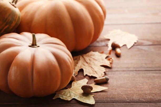 istock Orange pumpkins with dry leafs and acorns on wooden table 982364116