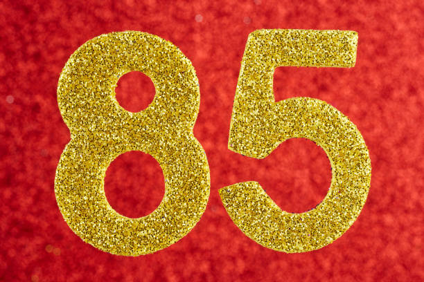 istock Number eighty-five golden color over a red background. Anniversary 982364452