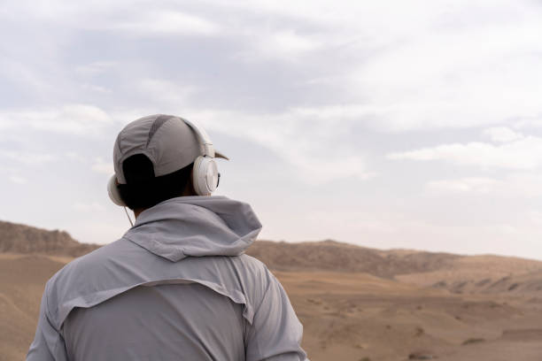 człowiek słuchający muzyki ze słuchawkami na pustyni gobi - sand dune audio zdjęcia i obrazy z banku zdjęć