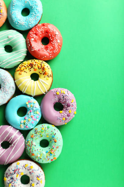 istock Tasty donuts with sprinkles on paper background 982364558